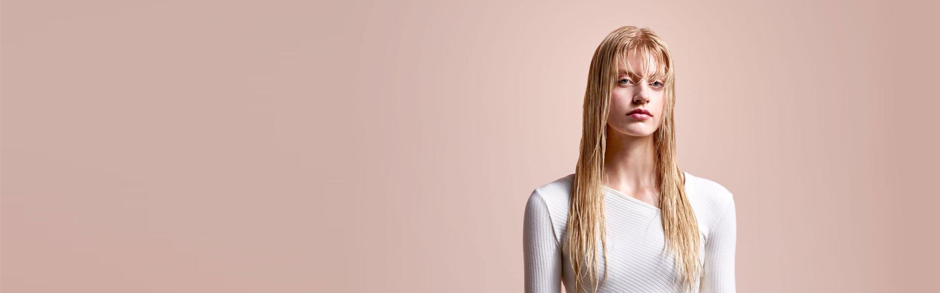 Model before straightening with damp, long blonde hair.